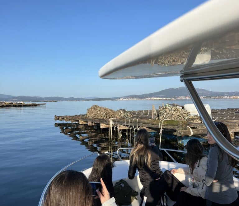Gente en un barco visitando las bateas de cultivo de mejillones en la Ría de Arousa